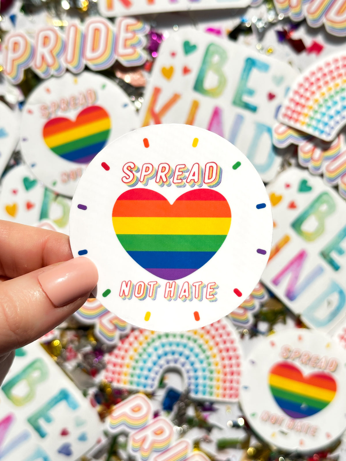 holding 2.5 in circle sticker spread love not hate rainbow heart laminate over vinyl sticker