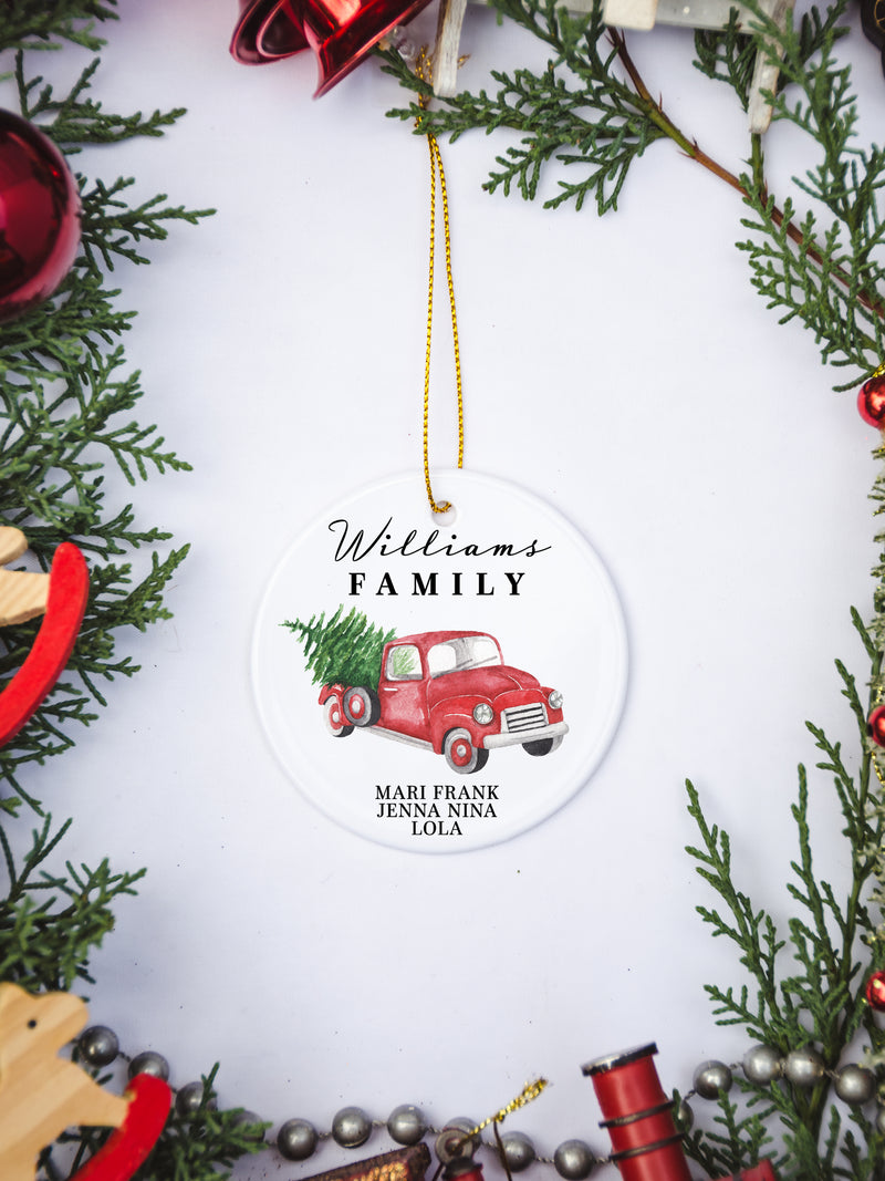 White circular ceramic ornament with the words Our First Christmas As Mr. & Mrs. followed by the family name in the center and the year. There is a red truck and Christmas Tree under name.  Black cursive font.  Ships with gold threaded ornament tie.